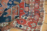 Antique Serapi rug's complex geometric border in red, navy, ivory, showing light tatter.