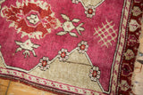 Corner detail of vintage Turkish Yastik rug, raspberry red field, floral motifs, and intact selvage.