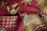 Close-up of the vintage Yastik rug's raspberry red pile, ivory pattern, and intact side cord.