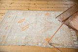 Distressed vintage Oushak rug displaying splayed bud border, soft ivory and tangerine tones.