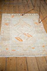 Distressed Oushak rug with muted ivory field, double gul medallions, and tangerine orange accents.
