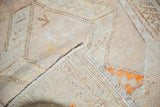Distressed Oushak rug corner showing worn pile, fringe, woven foundation, tangerine orange.