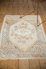 Distressed vintage Oushak rug showing faded tangerine, ivory, charcoal vinery, and spandrel motifs.