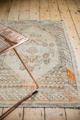 Textured fringe and faded tangerine diamond pattern on a distressed vintage Oushak rug corner.