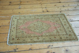 Distressed corner of antique Persian rug, showing light end tatter, intact side cord, and boteh design.