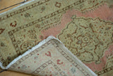 Detail of antique distressed Jalili Tabriz rug's low pile, dusty pink boteh, and hand-knotted back.