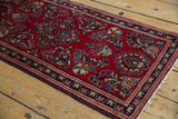 Vintage Sarouk runner corner with cherry red floral field, navy border, intact selvage, and fringe.