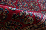 Dense floral sprays in cherry red, navy, and gold on a vintage Sarouk.
