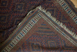 Antique Belouch rug corner detail, showing tattered ivory fringe, geometric pile, and woven foundation.