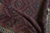 Antique Belouch rug's wine red ground with sharply serrated navy blue diamond motifs, wear, and tatter.