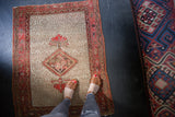 Worn corner of antique Malayer rug, showing red boteh main border detail.