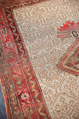 Antique Malayer rug detail: ivory field with geometric lattice and rich red border.