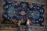 Hand-knotted Baktiari rug's indigo outlined medallion with detailed floral motifs and low pile.