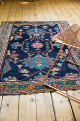 Hand-knotted Baktiari rug corner detail, highlighting indigo, blush, and saffron floral motifs with fringe.