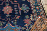 Baktiari rug: indigo field with blush, sky blue florals, low pile, and patterned border.