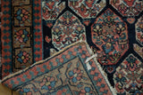 Folded Antique Northwest Persian rug showing tattered fringe, woven reverse, and blush floral border.