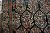 Antique Northwest Persian rug: tan floral border, navy field with oversized boteh motif.
