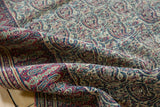 Folded antique Doroksh rug with intricate boteh paisley design and aged pile texture.