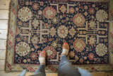 Antique Caucasian rug's dense navy field with time-softened red and ivory geometric motifs.