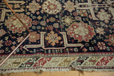 Detailed corner of an antique Caucasian rug, geometric patterns in navy, madder red, ivory, tattered fringe.