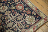 Intricate antique Caucasian rug, navy, madder red, ivory geometric floral motifs, visible wear, tattered edge.