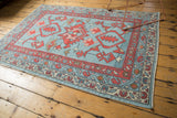 Oushak rug corner with faded blue field, madder red, ivory vine and boteh borders.