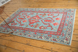 Oushak rug corner detail with repeating boteh border, primitive blossoms, blue and red tones.