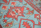 Detail of madder root red and blush primitive blossoms on a powder blue Oushak rug with vine border.