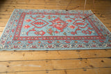Close-up of hand-knotted Oushak rug border showing madder red pattern and blue vine motifs.