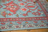 New Oushak rug corner displaying madder root red boteh border and faded denim blue vine motifs.