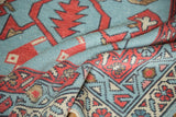 Folded detail of New Oushak rug showing geometric patterns in powder blue and madder red.