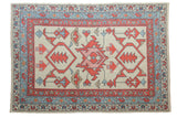 Hand-knotted Oushak rug with ivory field, oversize red palmette medallion, blue patterned borders.