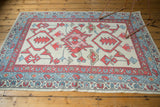Corner detail of New Oushak rug, showing primitive blossoms, vine, and red boteh border.