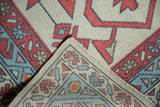 Hand-knotted Oushak rug corner revealing ivory, powder blue, and madder red pile and tight weave.