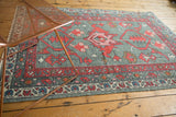 Oushak rug field with red splayed palmette, primitive blossoms, and traditional patterned borders.