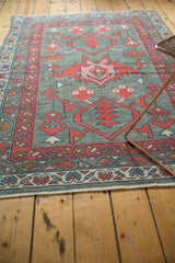 New Oushak rug corner with madder red boteh, blue vine border, and gray primitive blossoms.