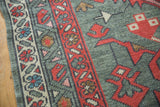 Oushak rug border showing meandering vine motif, red geometric elements, and primitive blossoms.