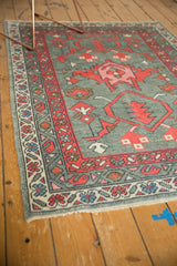 Angled view: New Oushak rug with oxidized gray field, red palmette, and detailed vine borders.