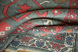 Hand-knotted Oushak rug's folded texture, revealing madder red boteh border and primitive blossoms.
