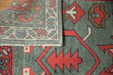 New Oushak rug folded, revealing blush vine border and oxidized silver gray field motifs.