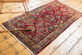 Rich cherry red field with intricate floral sprays in gold, celadon, and sky blue on a vintage Sarouk rug.
