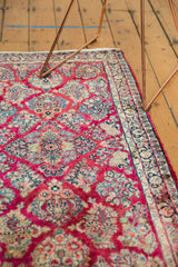 Glossy raspberry field with intricate floral sprays and tight weave on a Sarouk rug.