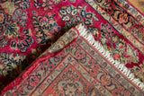Sarouk rug's folded corner reveals intricate floral field, tight hand-knotted foundation, and fringe.