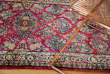 Intricate floral sprays in blue, green, and gold on the vivid raspberry Sarouk rug.