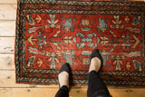 Close-up: vintage Lilihan rug with oversized floral pattern in cherry red and blues, visible wear.