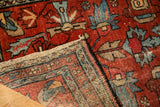 Vintage Lilihan rug's corner folded to show woven foundation and cherry red floral pile.