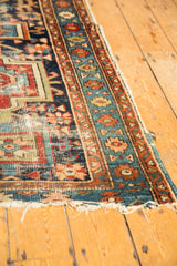 Antique Karaja rug border and field showing worn knot heads, navy blue, madder red geometric design, and tattered ends.
