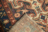Vintage Baktiari rug corner folds to show red blossom border, hand-knotted foundation, and tattered fringe.