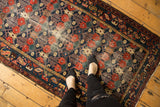 Vintage Baktiari rug pattern: cherry red florals, navy lattice, and ivory plant motifs.