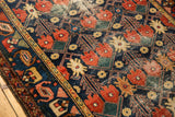 Vintage Baktiari rug detail: navy, red, green lattice with germinating plants and wear.